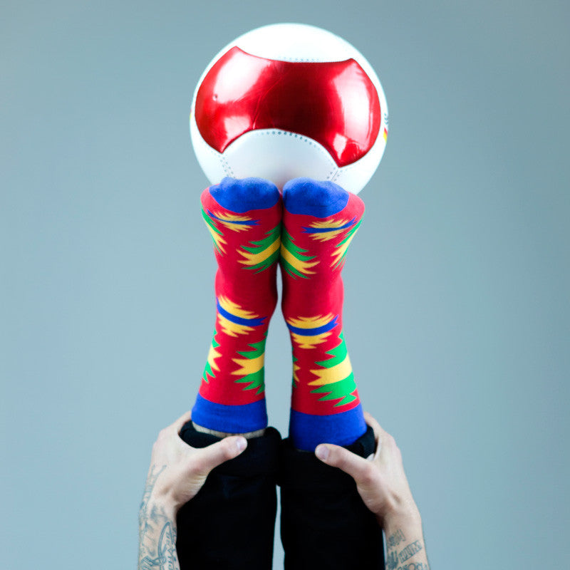 Colorful sock on feet with ball on top.